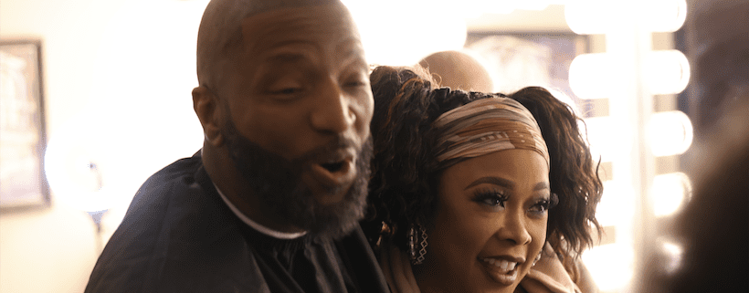 Two people smiling in a warmly lit room.